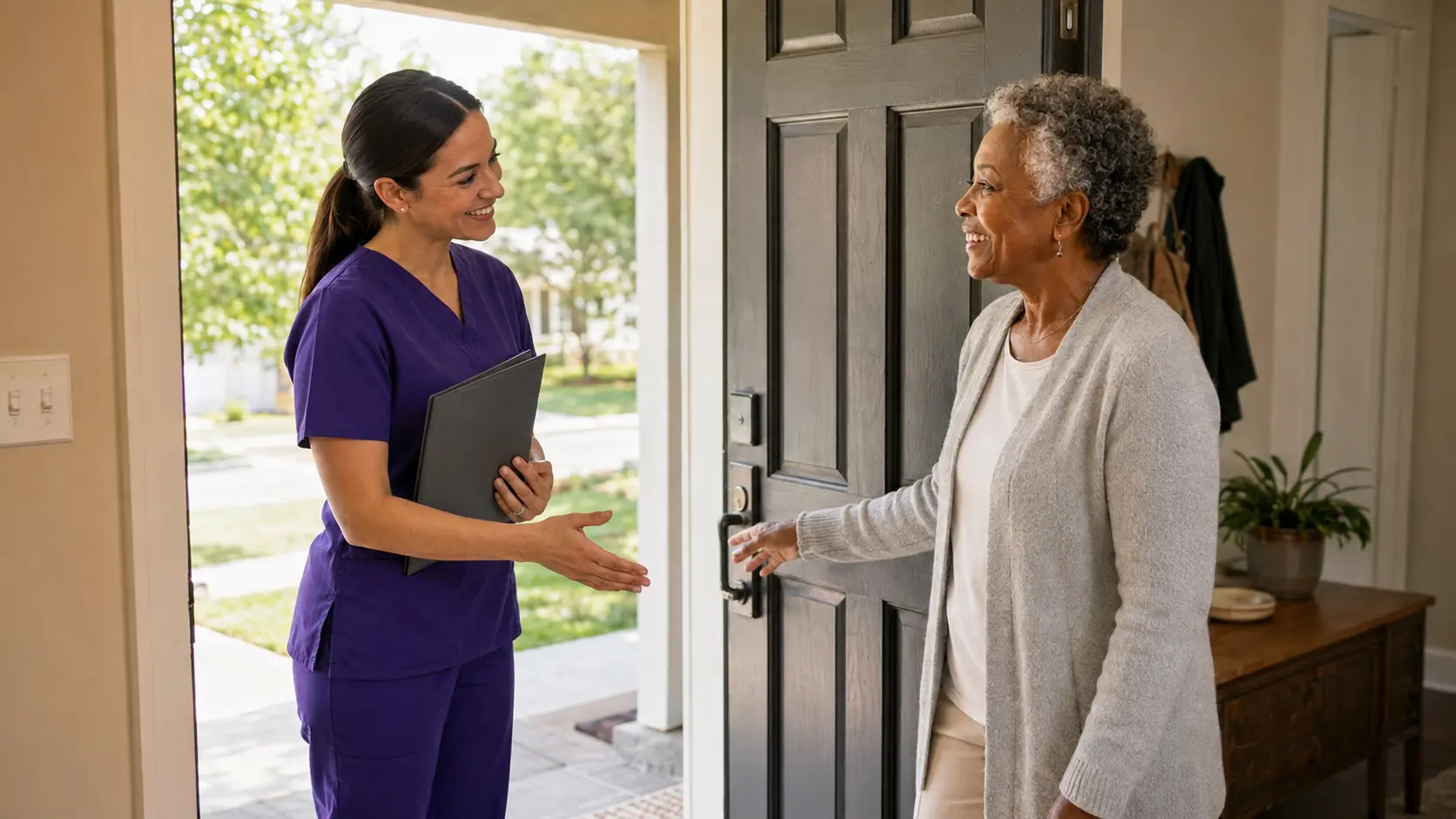An older adult warmly welcoming her caregiver at the front door